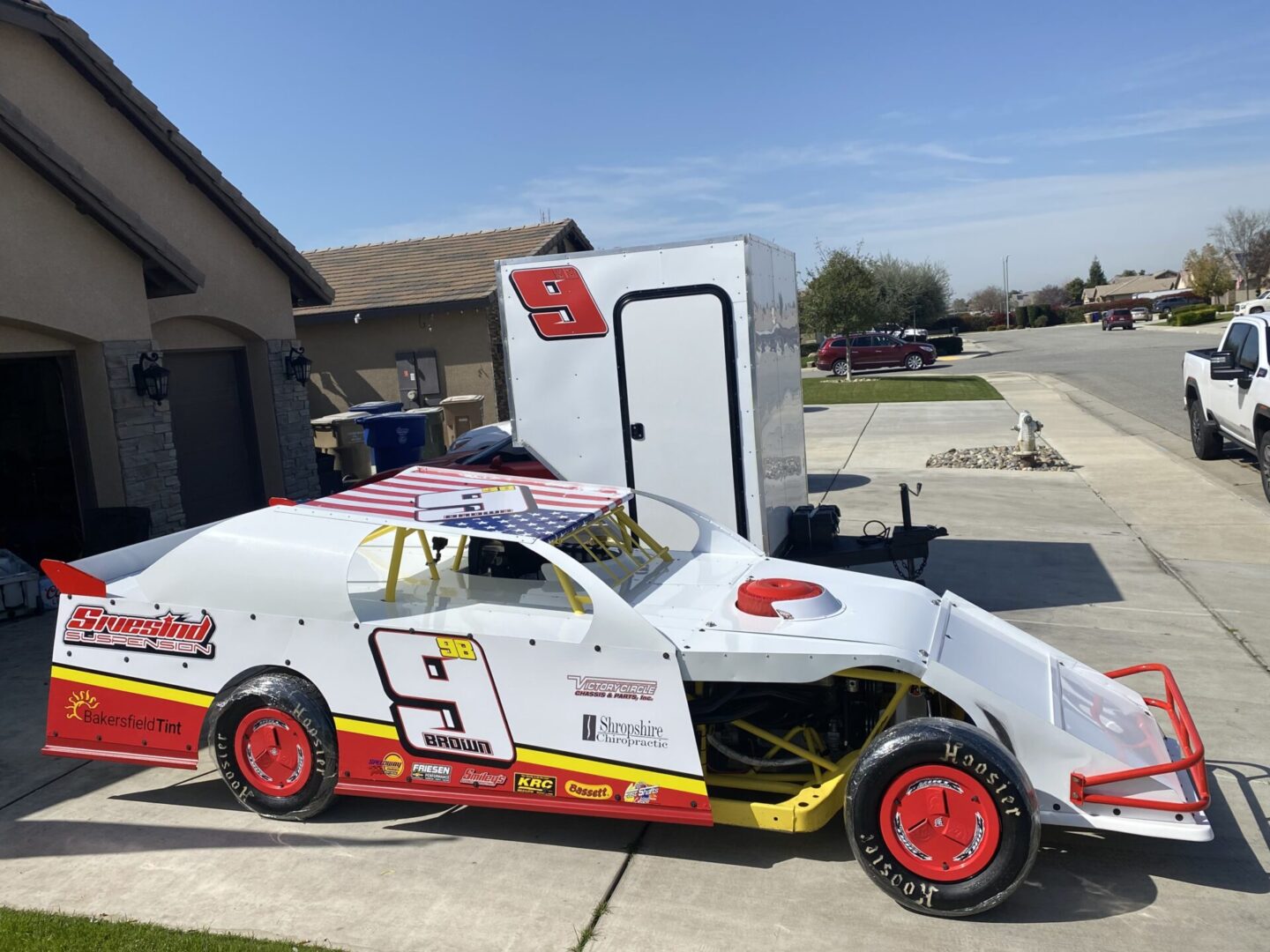 A white race car parked in front of a trailer.