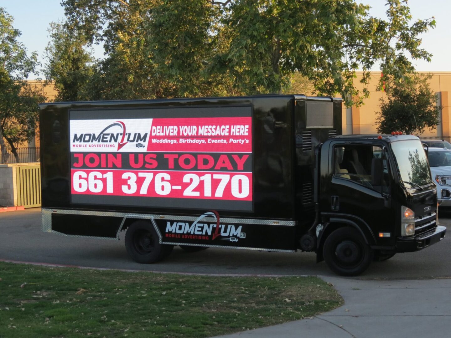 A black truck with a red sign on the side of it.